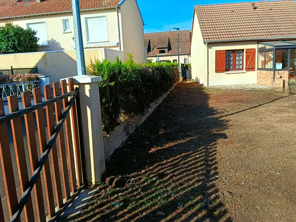 Le côté de la maison, la haie enlevée le long du muret