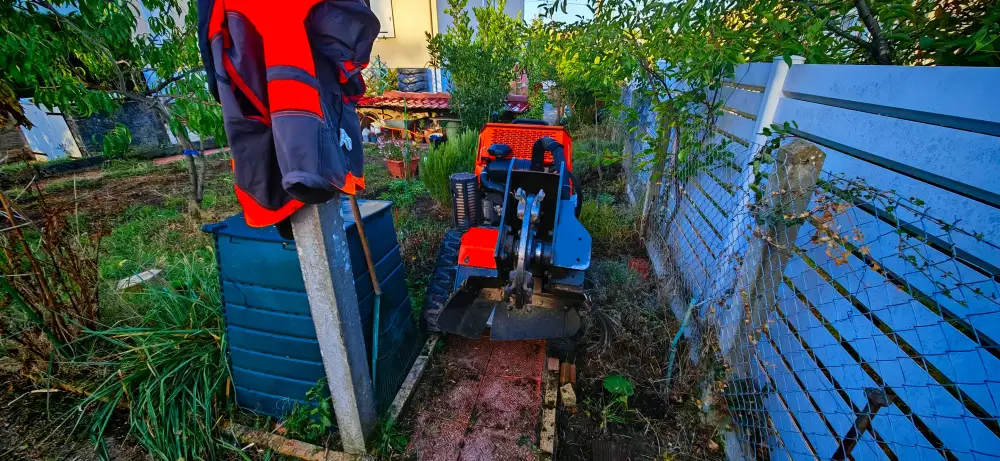Notre rogneuse sur chenilles glissée entre le composteur et le grillage, au fond d'un jardin de Parigné-l'Évêque